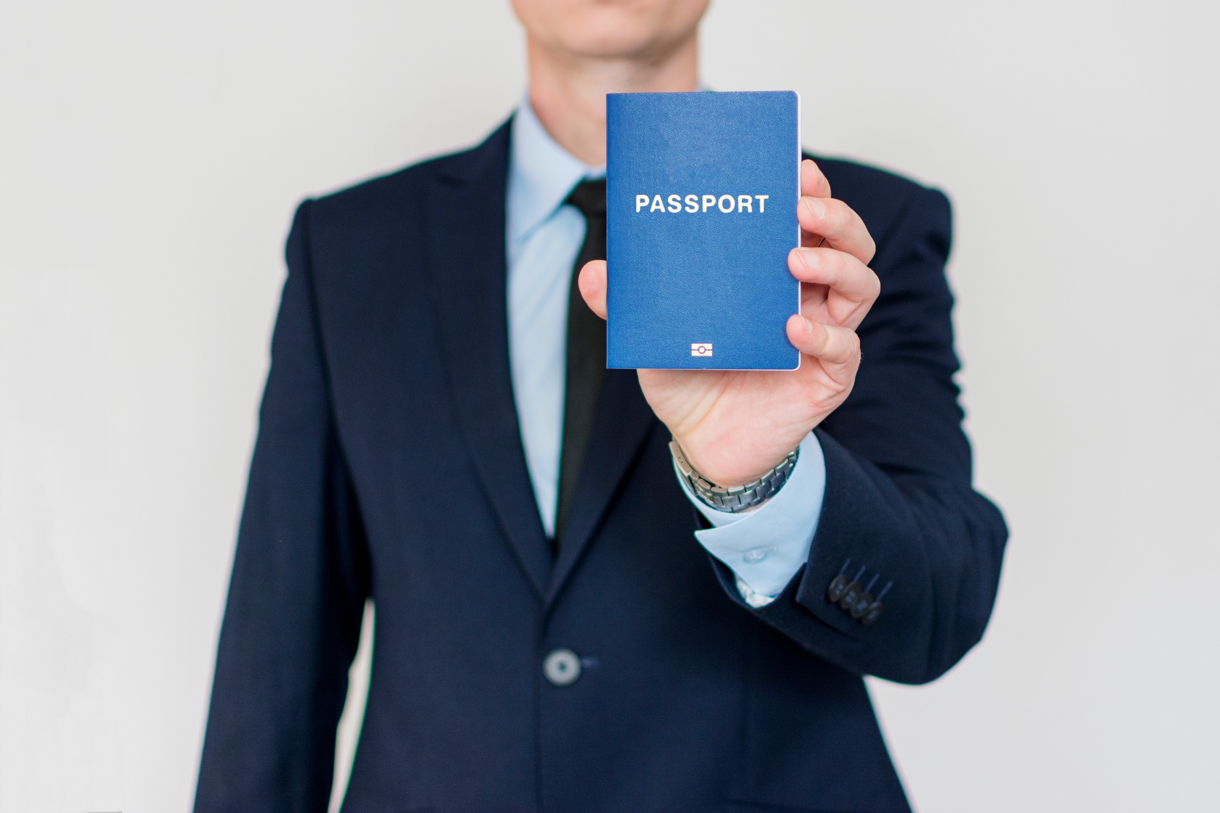A businessman holding a blue passport