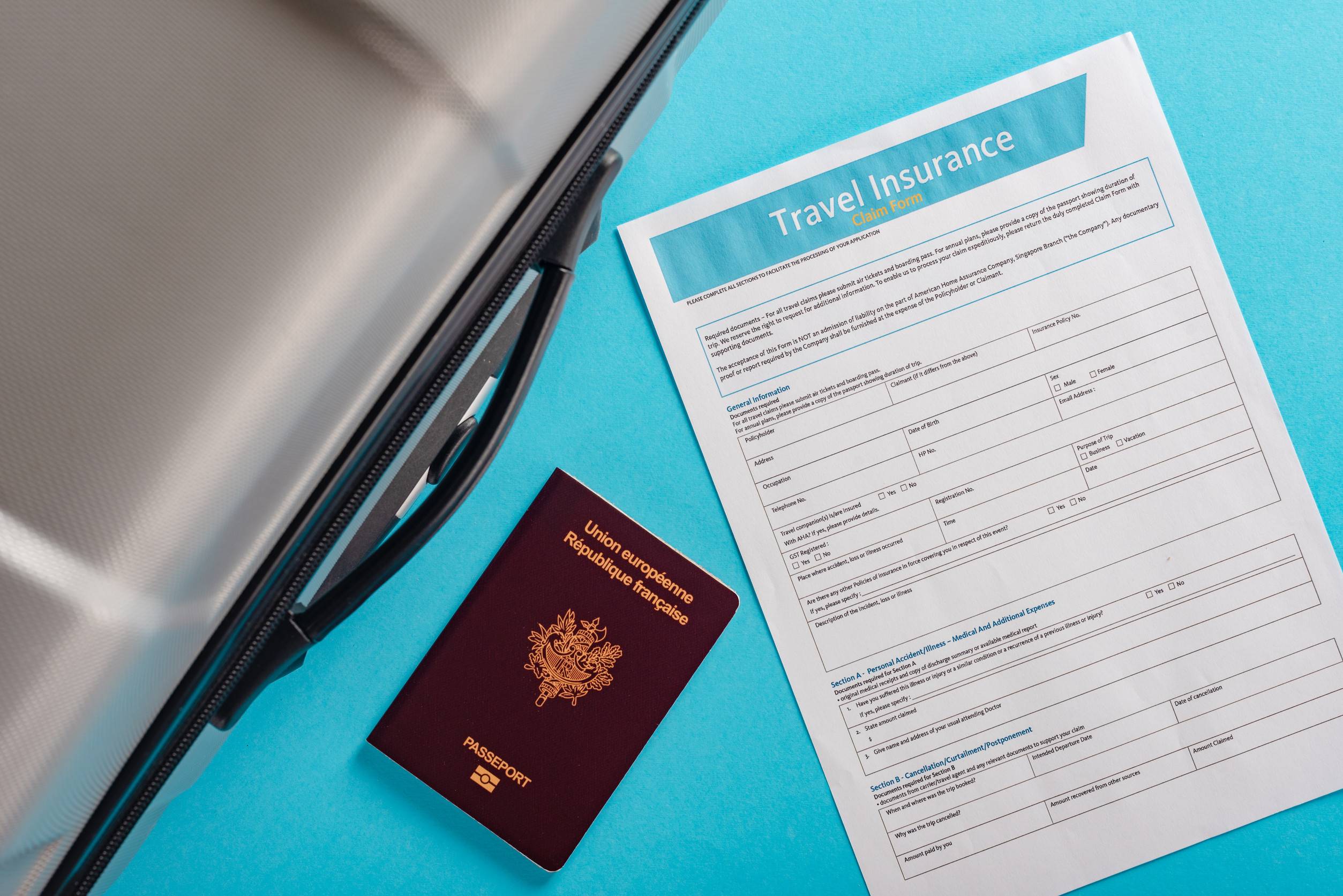 Travel Bag With French Passport And Insurance Form Isolated On Blue Background Travel Bag With French Passport And Insurance Form Isolated On Blue Background